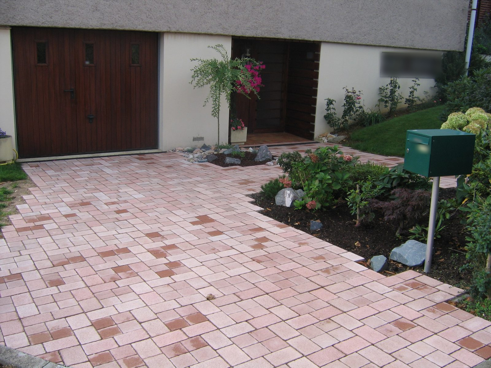Allée de garage en pavés rosés et massif fleuri